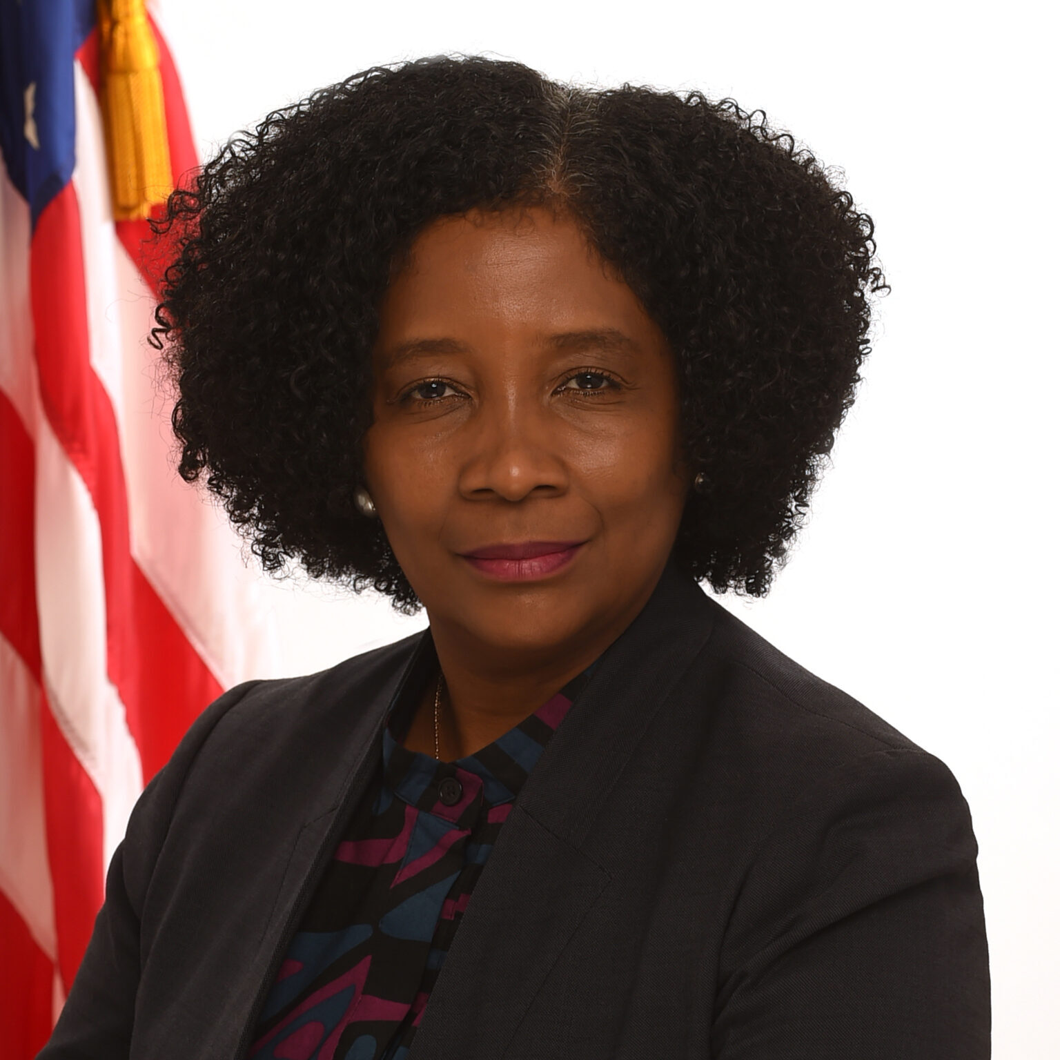 Aysha Schomburg, associate commissioner in the Children's Bureau in the Administration on Children, Youth and Families with American flag in the background.