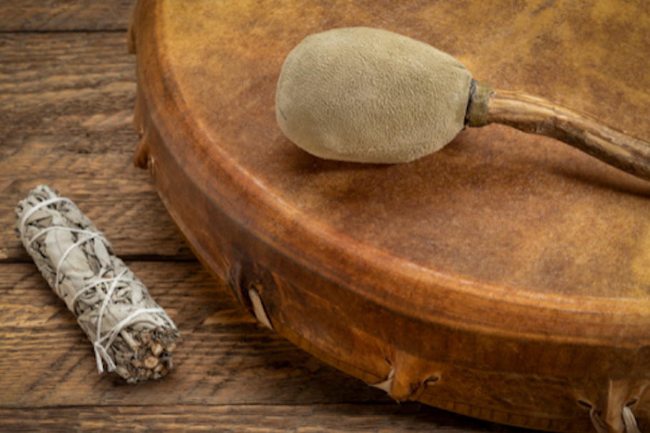 Sage stick laying next to a drum with a drum stick on top of it.